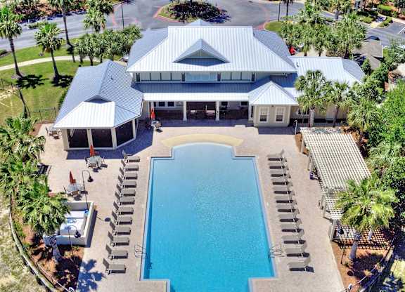 A large swimming pool surrounded by a fence and palm trees.