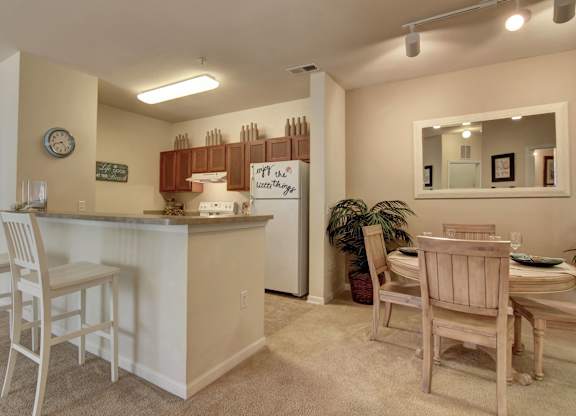 A kitchen with a bar and chairs.