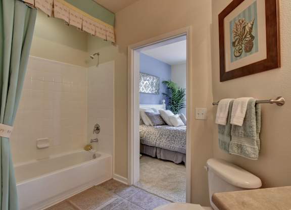 A bathroom with a green shower curtain and a white bathtub.