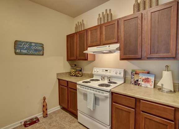 A kitchen with a white stove and wooden cabinets.