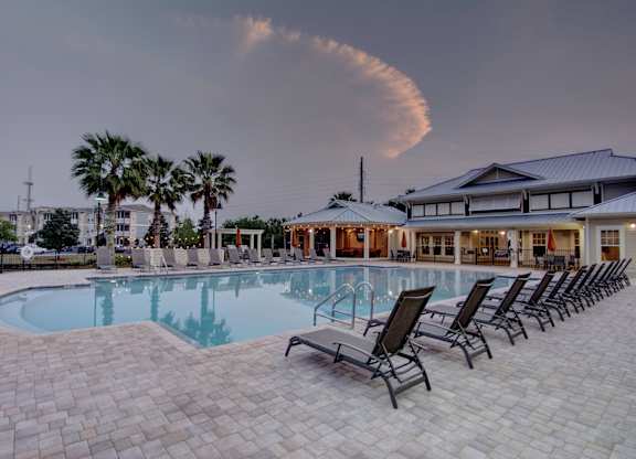 A swimming pool surrounded by lounge chairs and palm trees.