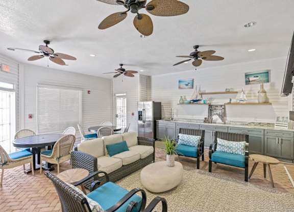 A living room with a couch, chairs, and a ceiling fan.