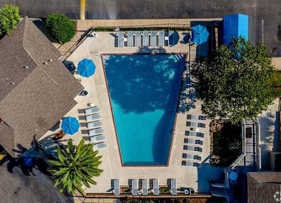 An aerial view of a swimming pool surrounded by lounge chairs and umbrellas.