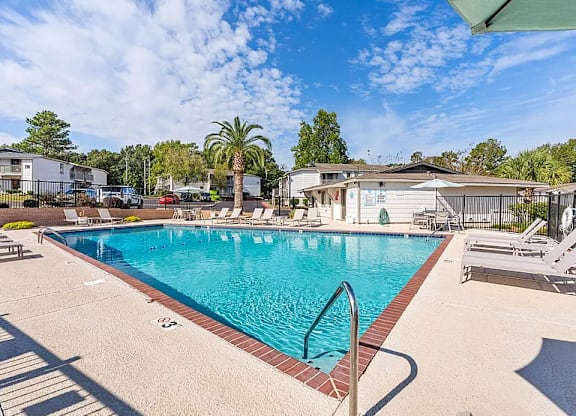 A large swimming pool with a metal ladder and a red brick border.