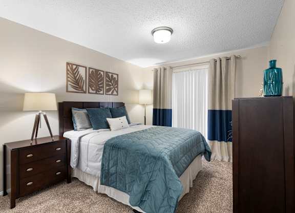 A bedroom with a bed, nightstand, and lamp.