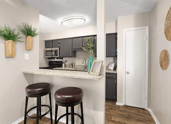 A kitchen with a white countertop and brown stools.