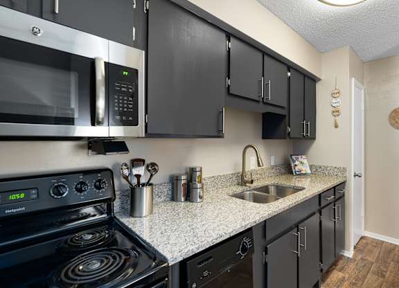 A kitchen with black cabinets and a stove top oven.