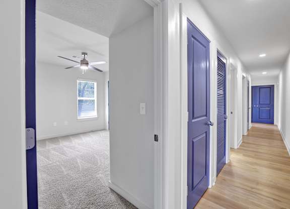 a hallway with blue doors and a ceiling fan