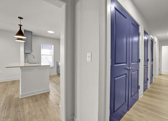 a hallway with blue doors leading to a kitchen and a counter top in a house