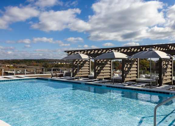 A swimming pool with a metal railing and umbrellas at 2020 Providence in Huntsville, AL