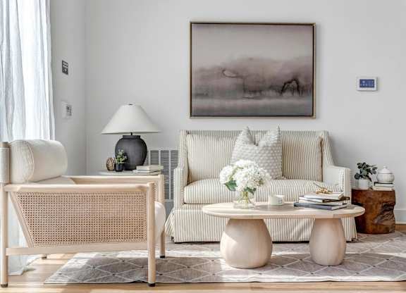 A living room with a couch, a table, and a painting on the wall.