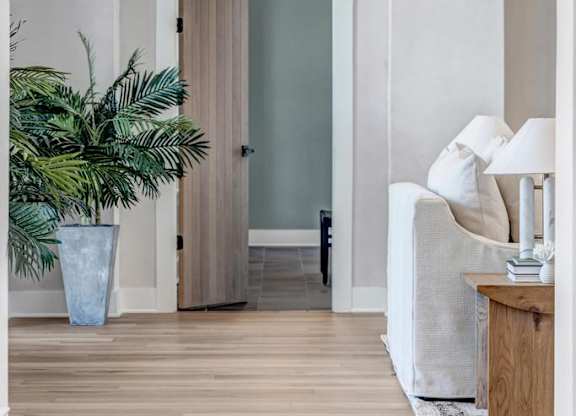 A room with a wooden floor and a white wall with a doorway.