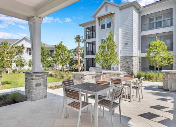 A patio with a table and chairs is surrounded by apartment buildings.