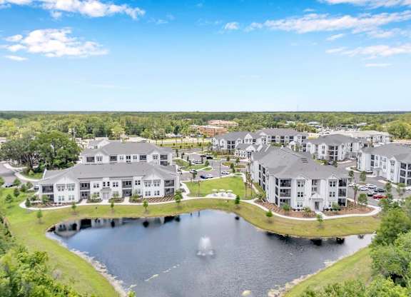 A large building complex with a pond in front and a lake in the background.