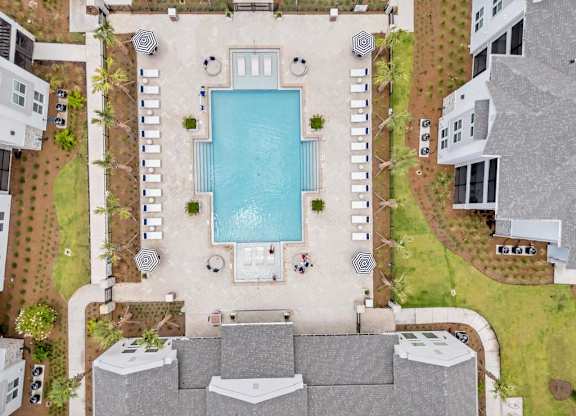 A large swimming pool surrounded by a concrete patio and lounge chairs.