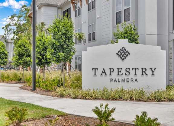 A sign for Tapestry Palmera in front of a building.