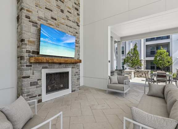 A modern living room with a stone fireplace and a flat screen TV mounted above it.