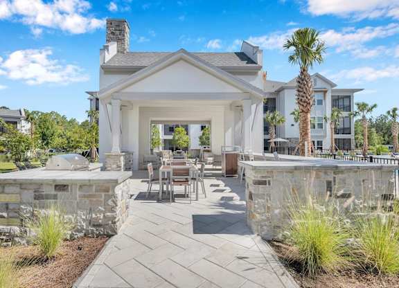 A white house with a stone wall and patio.