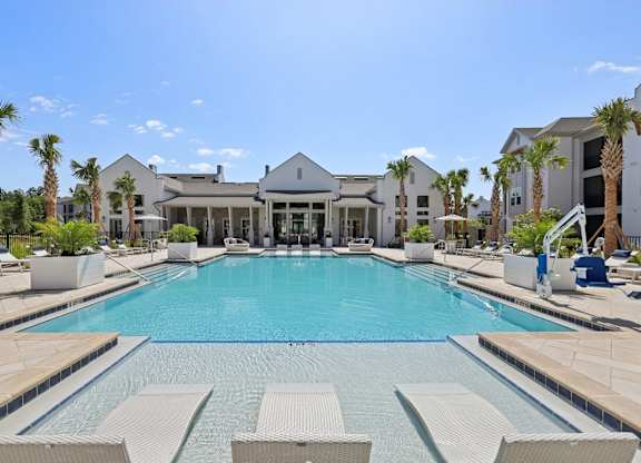 A large swimming pool surrounded by lounge chairs and palm trees.