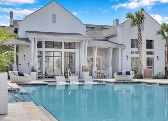 A white house with a pool in front.