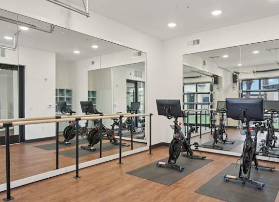 A gym with a mirrored wall and exercise bikes at Tapestry University Park in Sarasota, FL