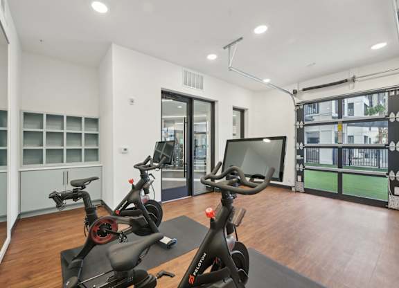 A gym with a treadmill, exercise bike and a television at Tapestry University Park in Sarasota, FL
