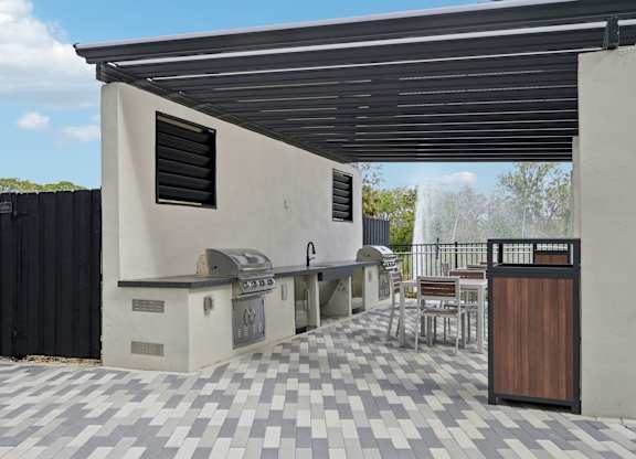 A modern outdoor kitchen area with a grill and sink at Tapestry University Park Apartments in Sarasota, FL