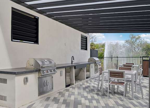 Outdoor kitchen with tables and chairs and a tv at Tapestry University Park Apartments in Sarasota, FL
