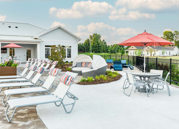 a patio with lounge chairs and umbrellas at Anthem Apartments and Cottages in Huntsville, Alabama