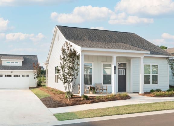 the exterior of a white house with a porch and a driveway