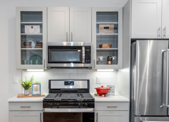 a kitchen with white cabinets, glass door fronts, and stainless steel appliances at Anthem Luxury Rentals and Apartment Homes in Huntsville, AL