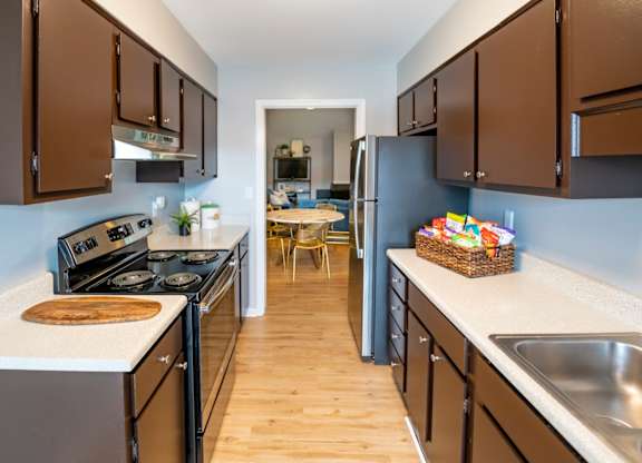A kitchen with brown cabinets stainless steel appliances at Saddlebrook at Tates Creek Apartments in Lexington, KY