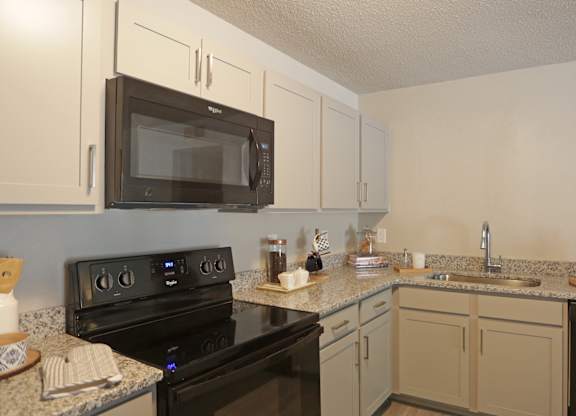 Kitchen with black appliances, gooseneck fauces, and granite countertops at Avia Apartments in Vestavia Hills, AL