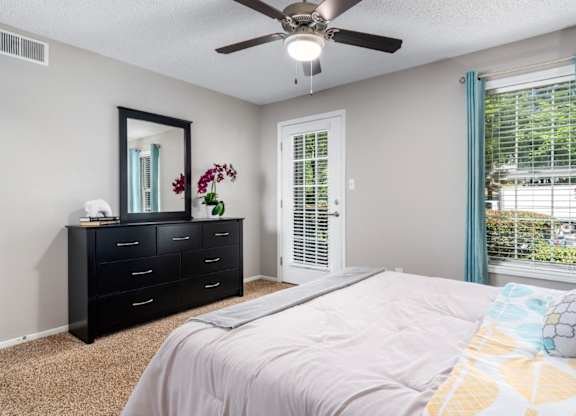 Carpeted bedroom with ceiling fan, door to patio at Summerchase at Riverchase in Hoover, Alabama