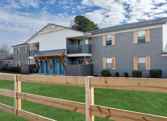 A wooden fence in front of a grey building at Magnolia Apartments in Athens, Alabama