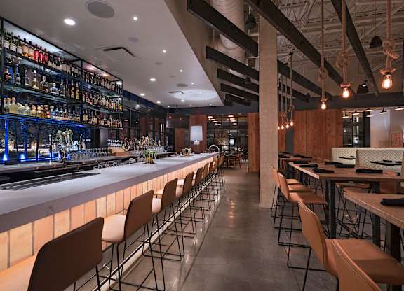 A bar with a long counter and chairs on either side.