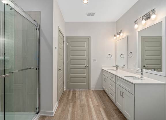 A bathroom with a walk-in shower, double sinks, and a large mirror.