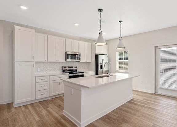 A kitchen with a white island and wooden floors.