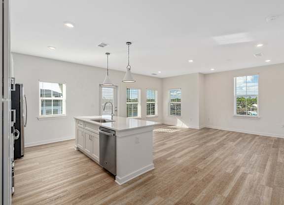A spacious kitchen with wooden floors and white cabinetry.