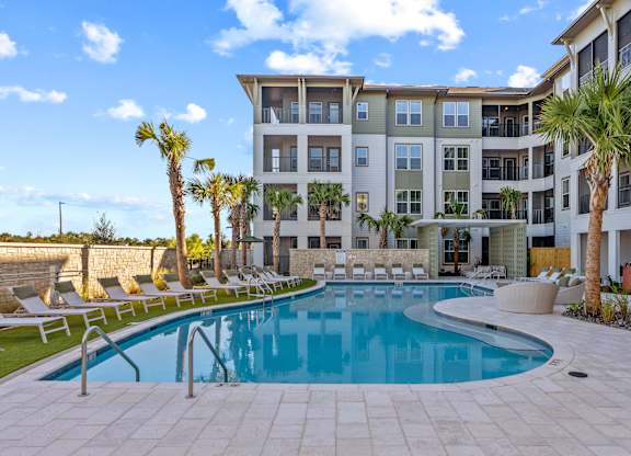 A large swimming pool in front of a multi-story apartment building.