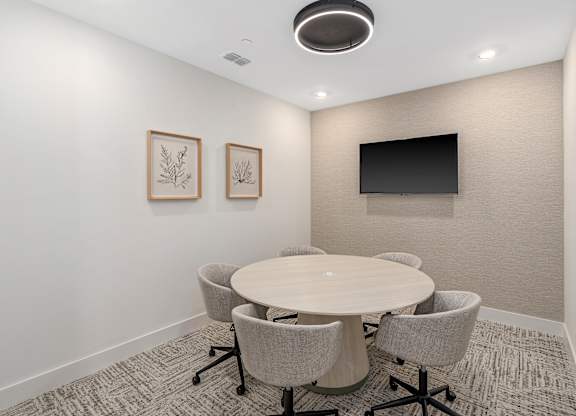 A conference room with a round table and chairs.
