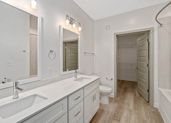 A white bathroom with a sink, toilet, and mirror.