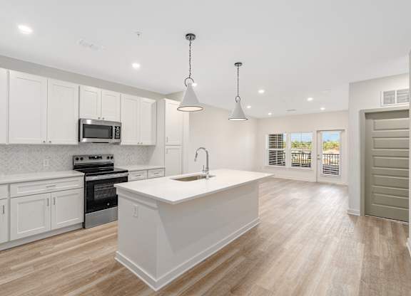 A kitchen with white cabinets and a white island.