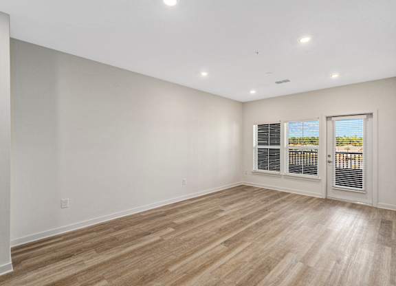 A room with wooden flooring and a sliding glass door.