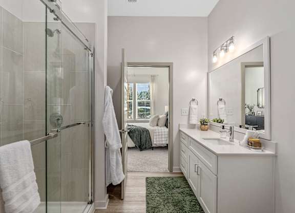 A bathroom with a glass shower stall, a white sink, and a mirror.