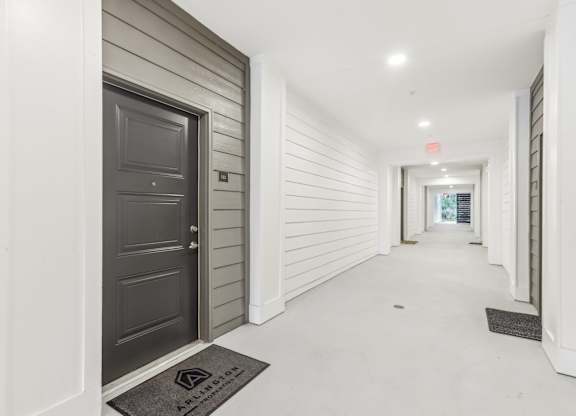 a long hallway with a black door and white walls