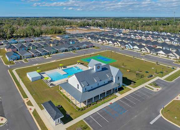 A large building with a pool in front of it is surrounded by a parking lot.