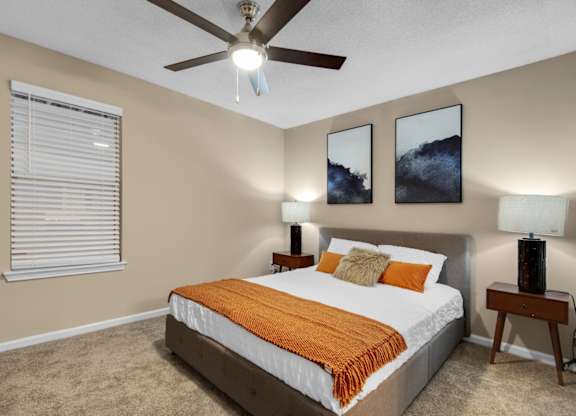 A bedroom with a bed, two nightstands, a window, and a ceiling fan at Crystal Lake in Pensacola, Florida.