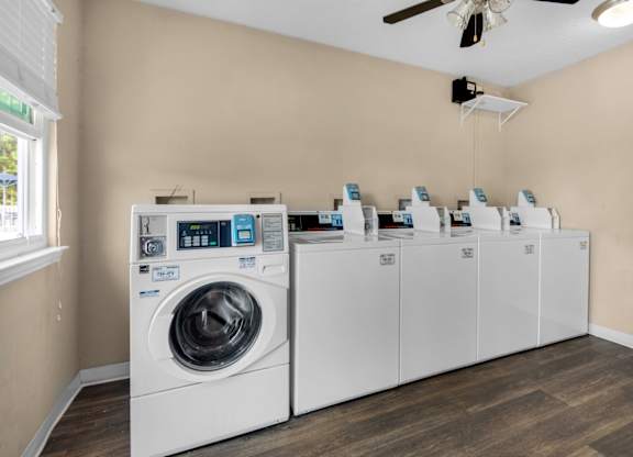 A washing machine and a row of dryers in a laundry room at Crystal Lake in Pensacola, Florida.