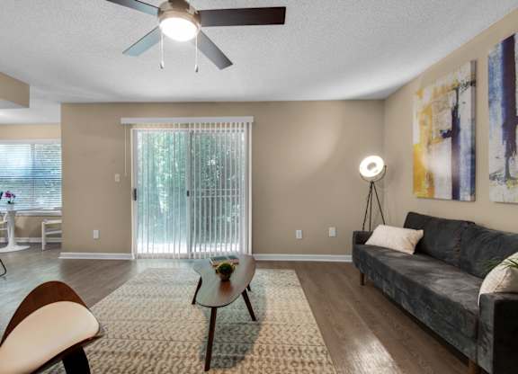A living room with a ceiling fan and a sliding door at Crystal Lake in Pensacola, Florida..